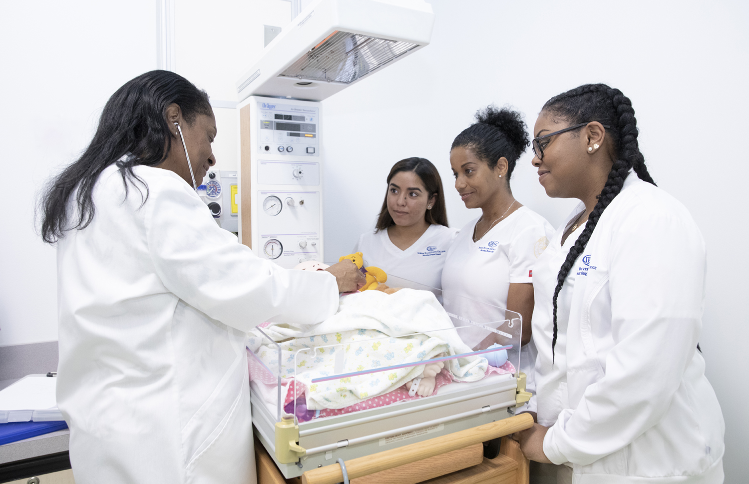A nursing instructor and three students gather around medical equipment during an Indian River State College nursing class.