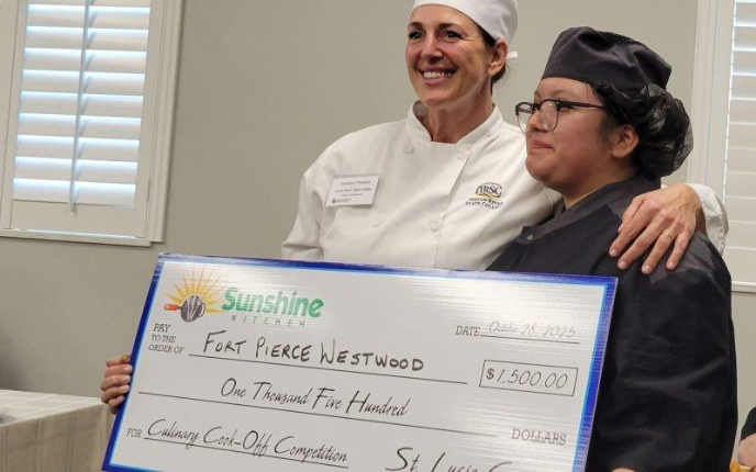 Two scholarship winners, Nimsi R. Moreno from Fort Pierce Westwood Academy and Christina Theriault from Indian River State College Culinary Institute, pose together while holding a large ceremonial check for $1,500 at the 5th Annual Sunshine Kitchen Cookoff