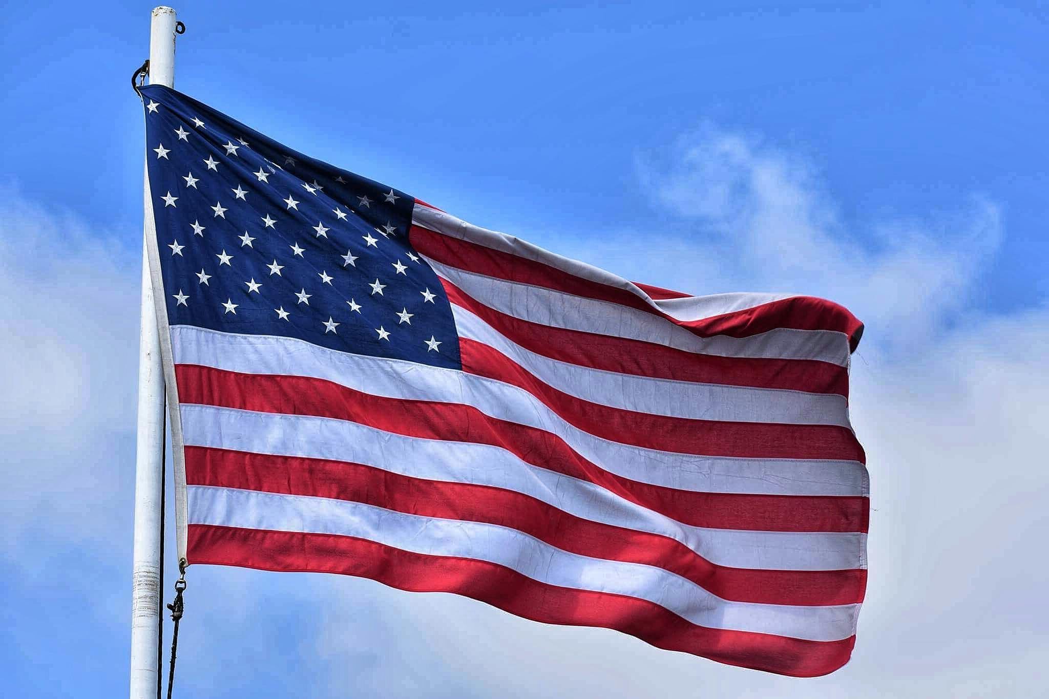 The American flag waving majestically against a vibrant blue sky, symbolizing patriotism and freedom.